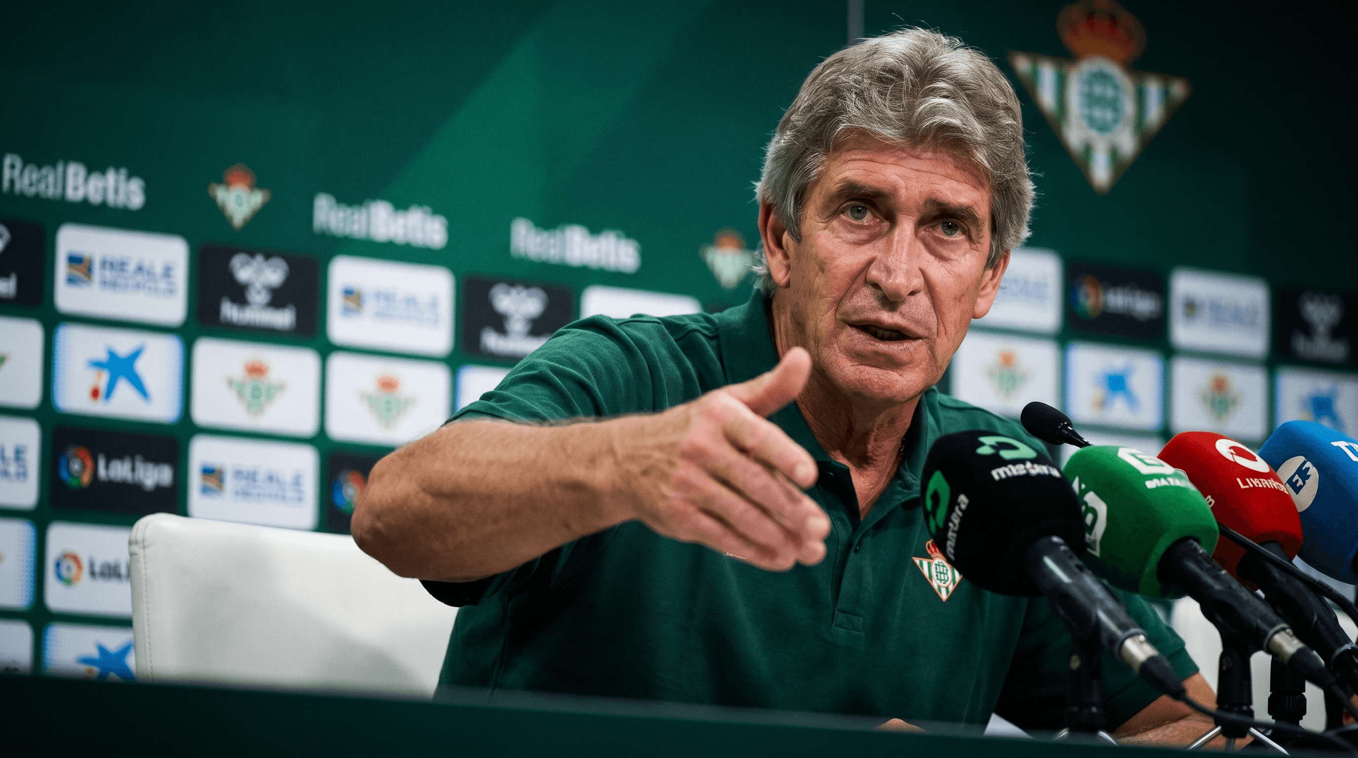 Manuel Pellegrini, entrenador del Real Betis, en una rueda de prensa, gesticulando mientras habla sobre la necesidad de inversión para la Champions League.